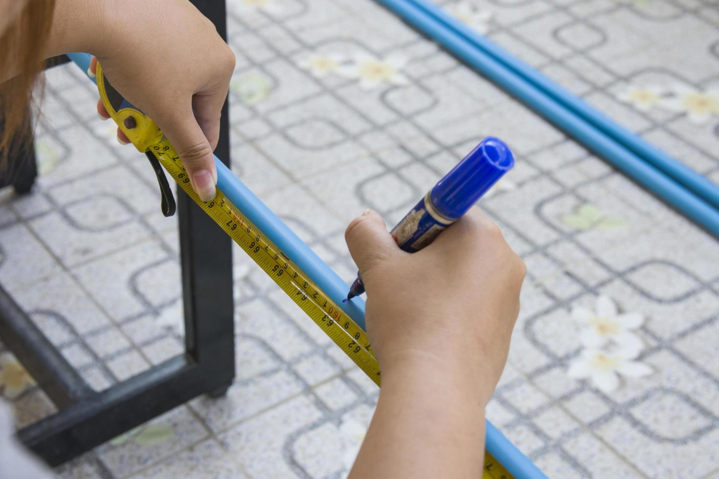 Workers use tape measure to measure PVC pipe length photo