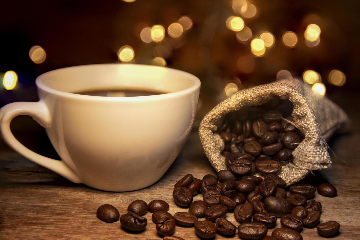 granos de café tostados, bolsas y taza de café con leche foto