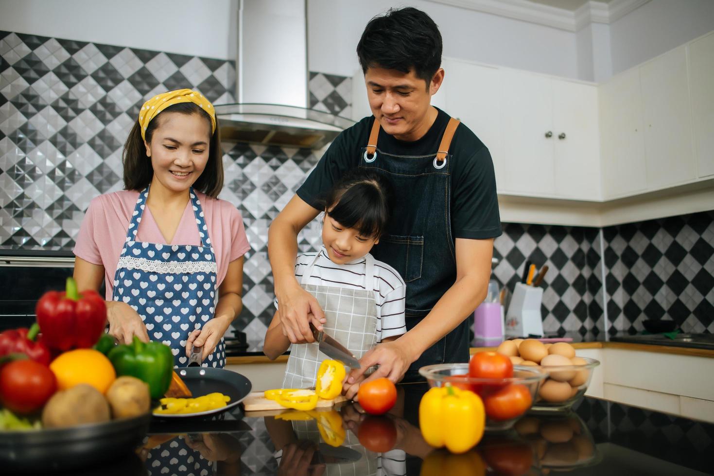 familia feliz cortando verduras juntos en su cocina foto