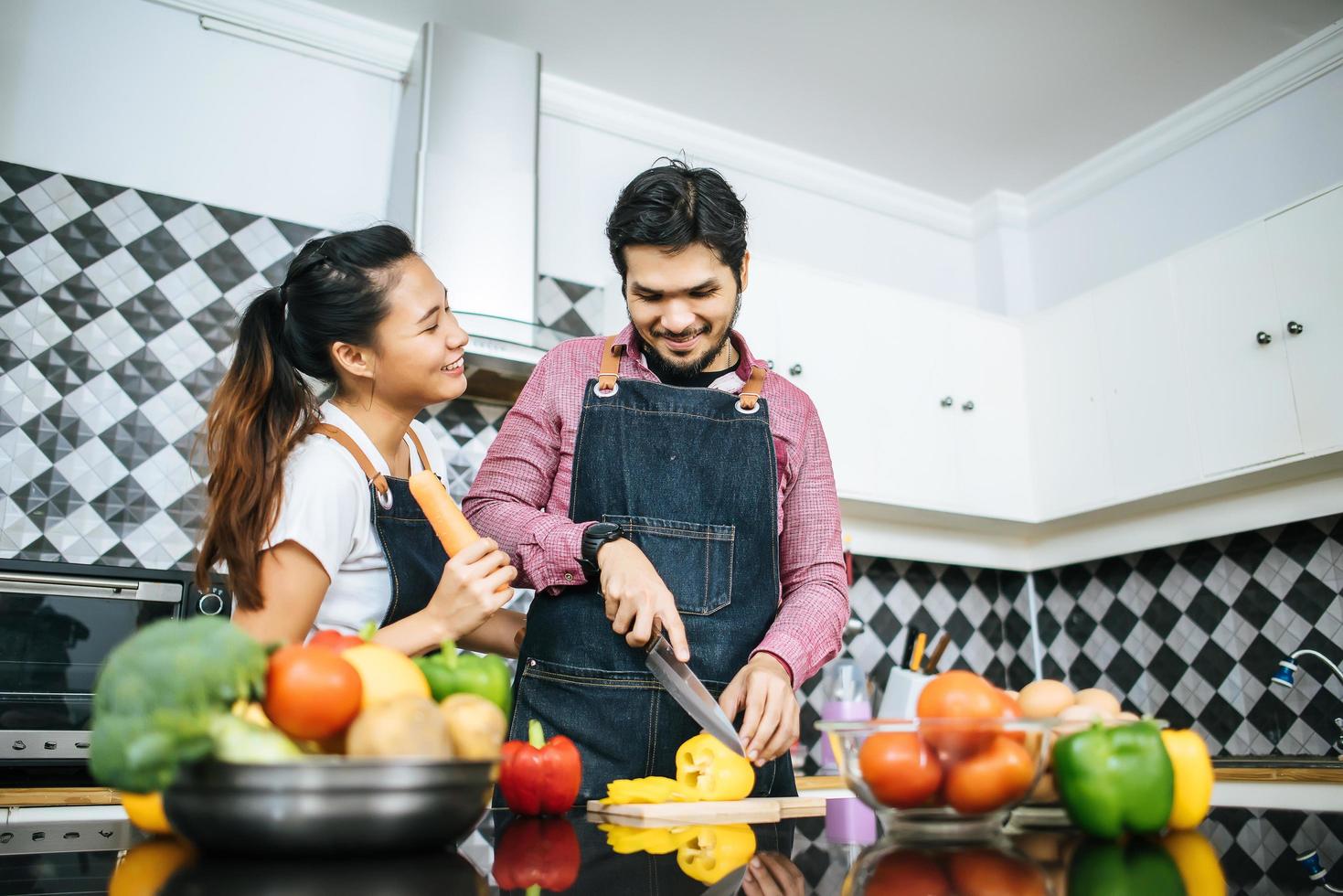 Happy young couple preparing food for cooking in kitchen at home photo