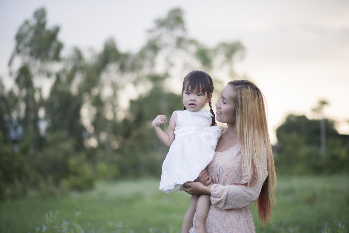 Mother and little daughter playing together in a meadow photo