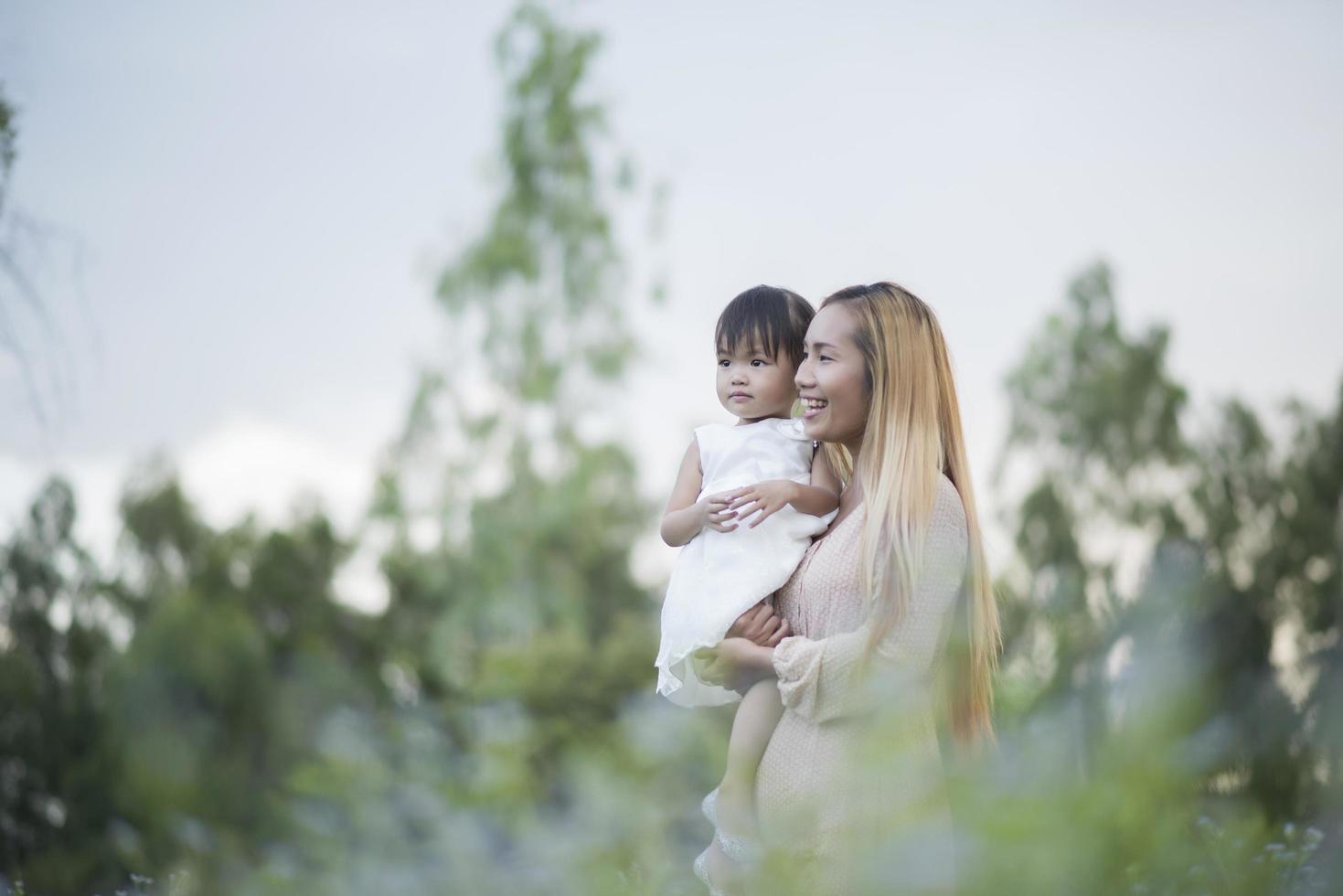 Mother and little daughter playing together in a meadow photo