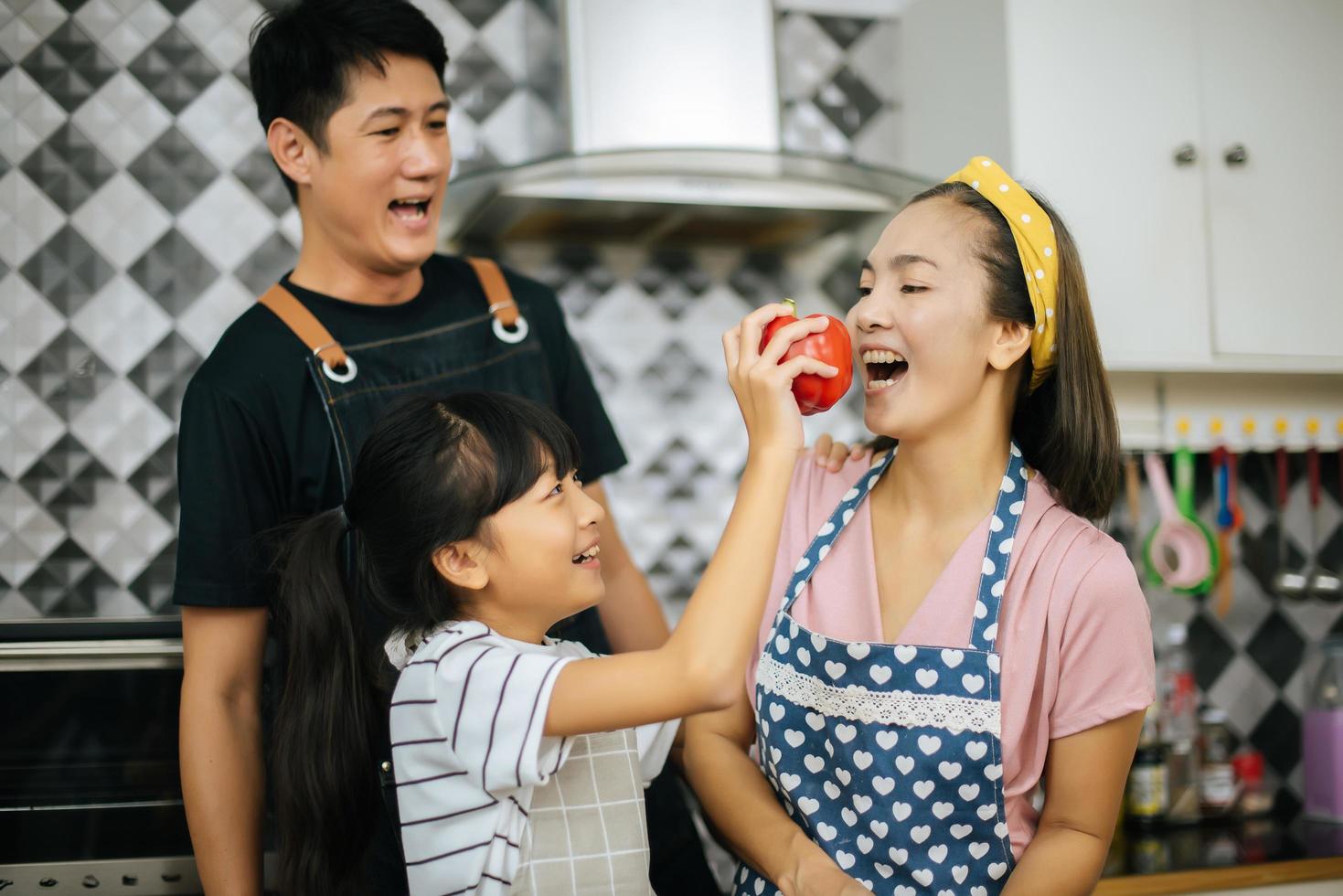 Happy family cutting vegetables together in their kitchen photo