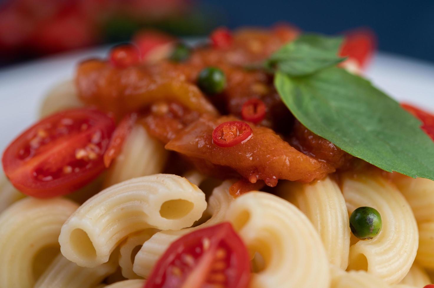 macarrones salteados con tomate, chile, semillas de pimiento y albahaca foto