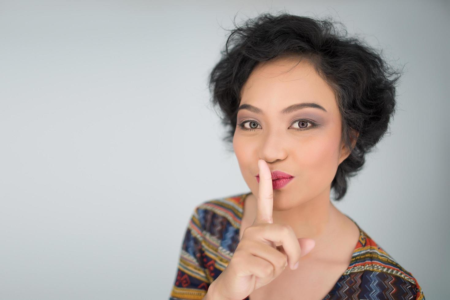 Young woman makes silent gesture on white background photo