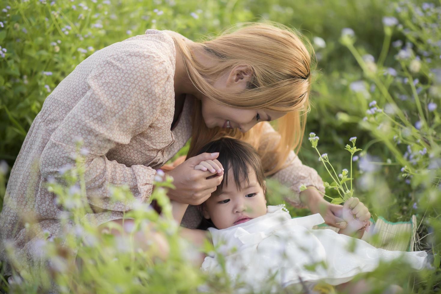 Mother and little daughter playing together in a meadow photo