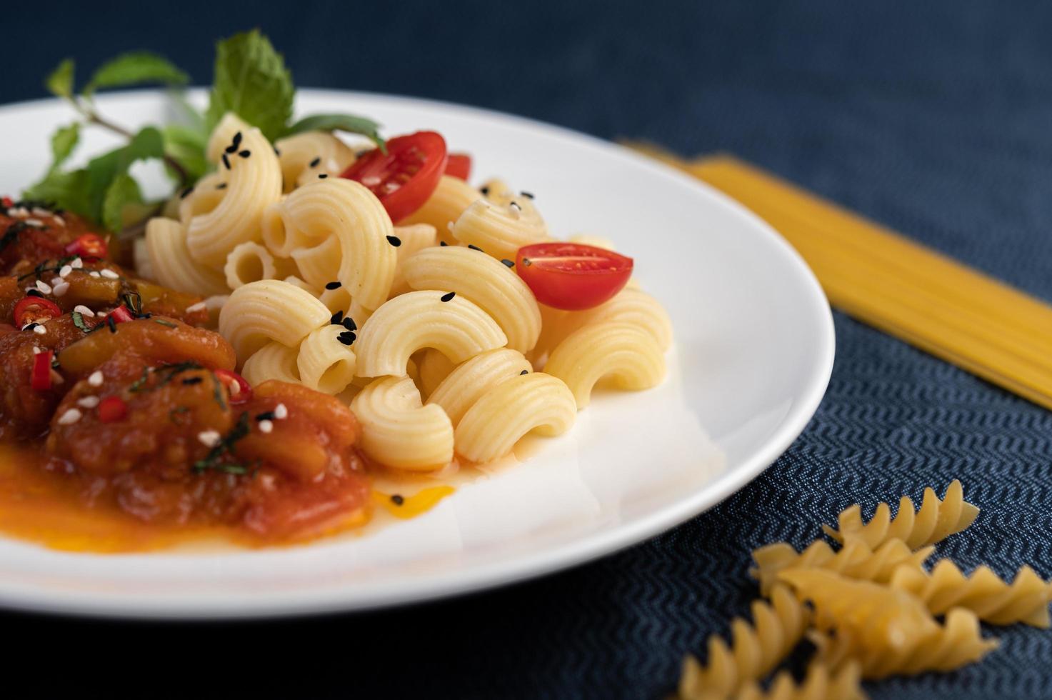 Stir-fried macaroni with tomato, chili, pepper seeds and basil photo