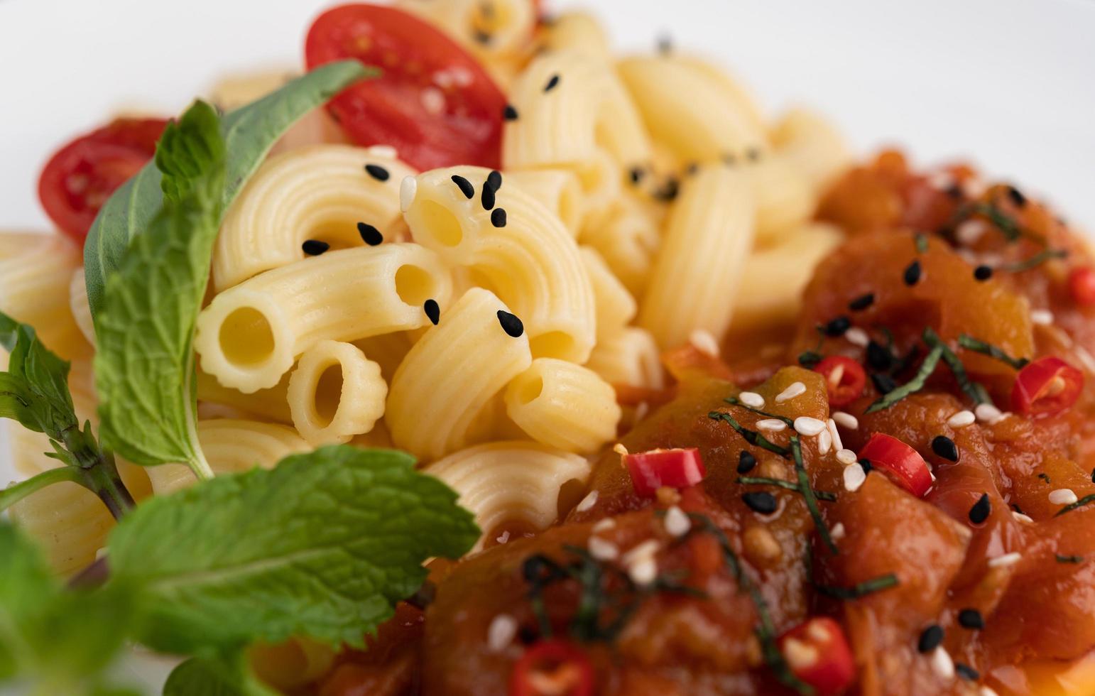 Stir-fried macaroni with tomato, chili, pepper seeds and basil photo