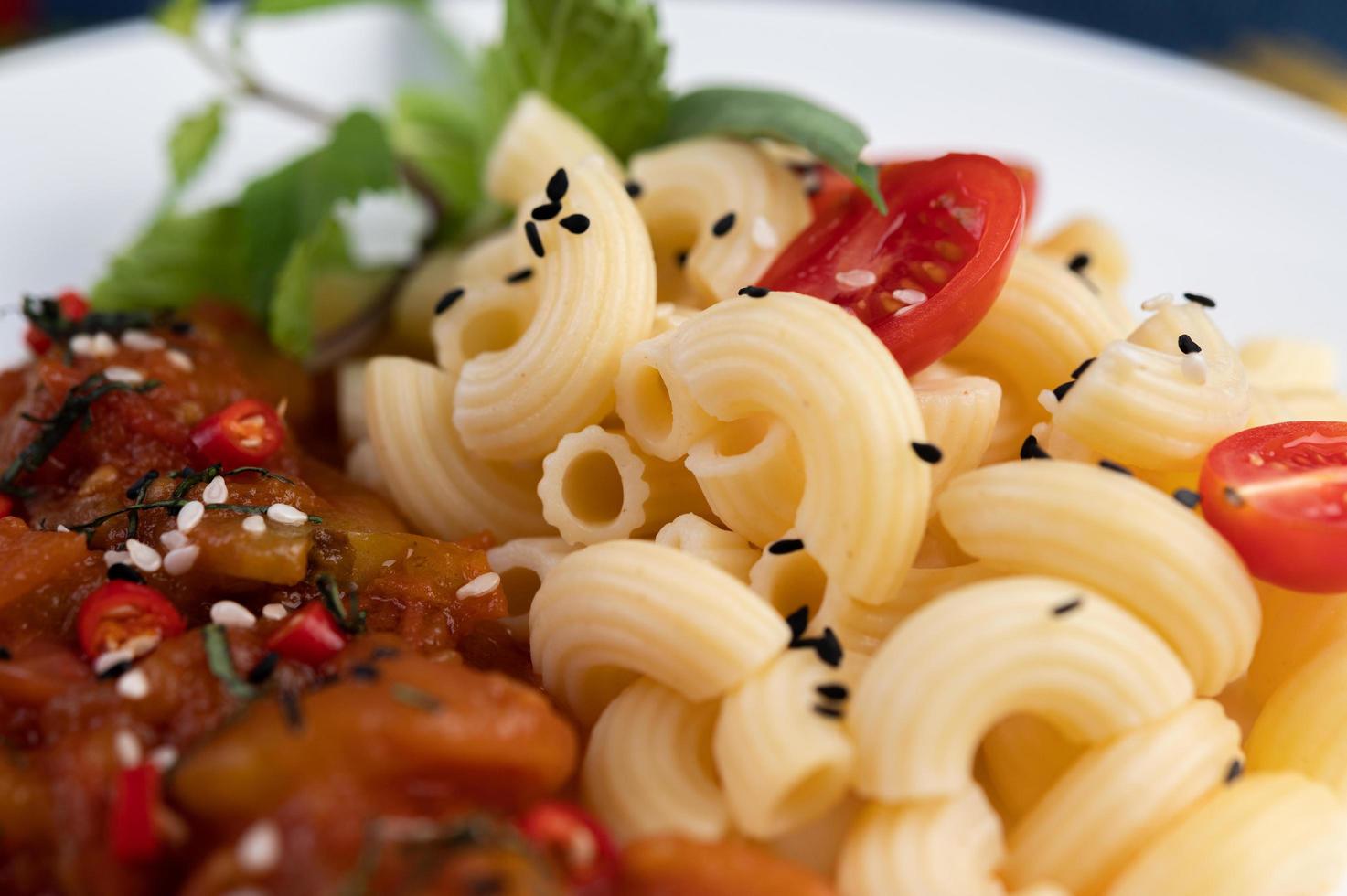 macarrones salteados con tomate, chile, semillas de pimiento y albahaca foto