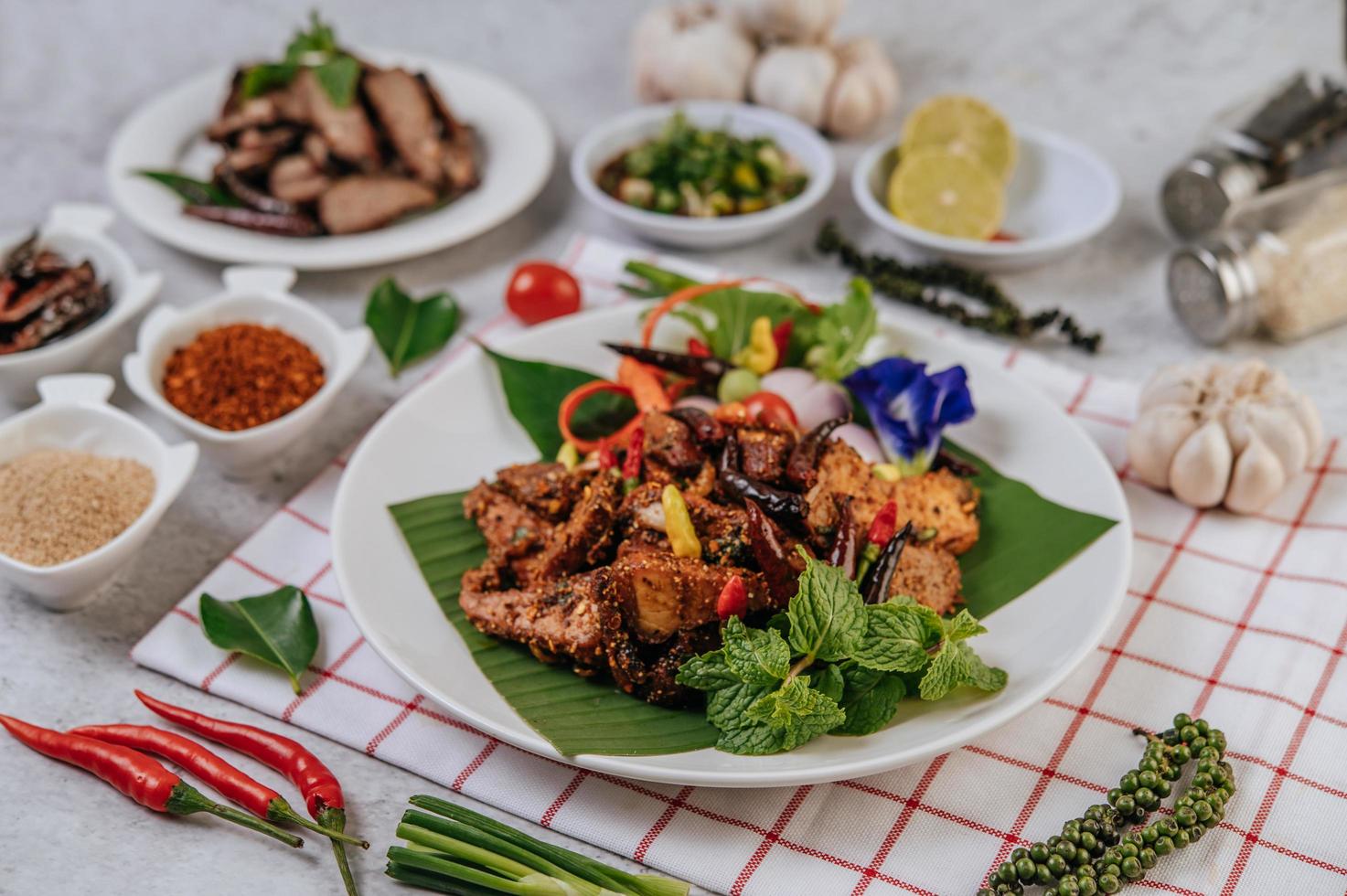 Pork Nam Tok with fried chili, tomato, lime, cucumber, and pepper photo