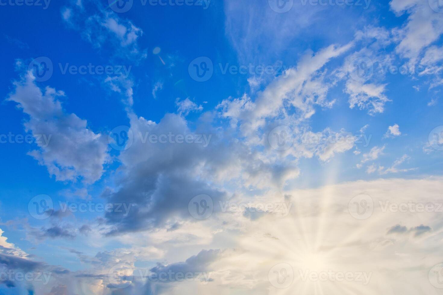 The sun shines through the clouds in a blue sky photo