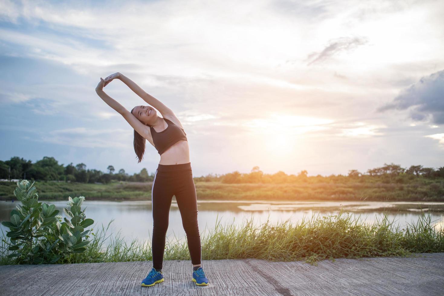 Mujer joven sana calentando al aire libre para entrenar foto