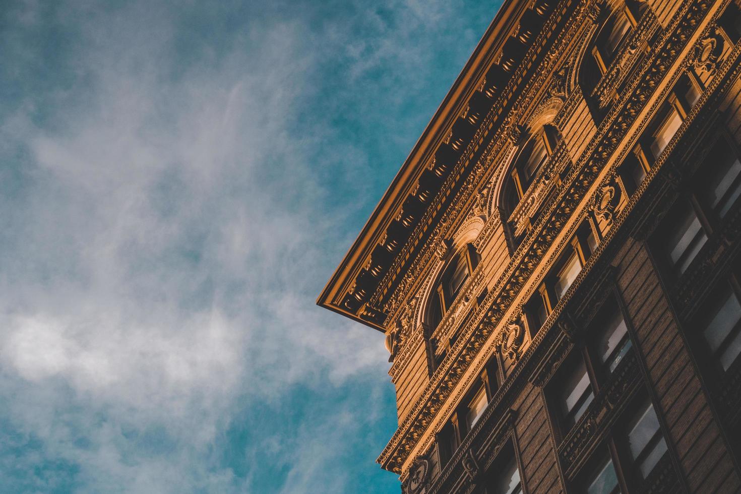 Corner of brown building with cloudy blue sky photo