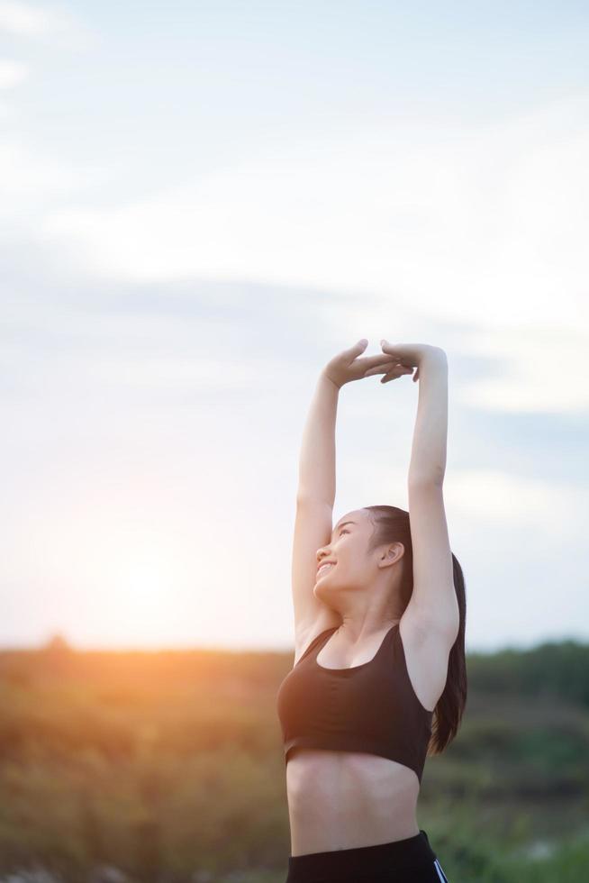 Mujer joven sana calentando al aire libre para entrenar foto