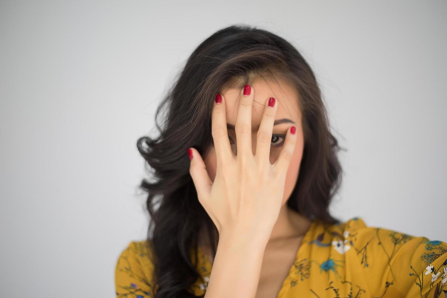 Beautiful young woman covers face with her hands photo