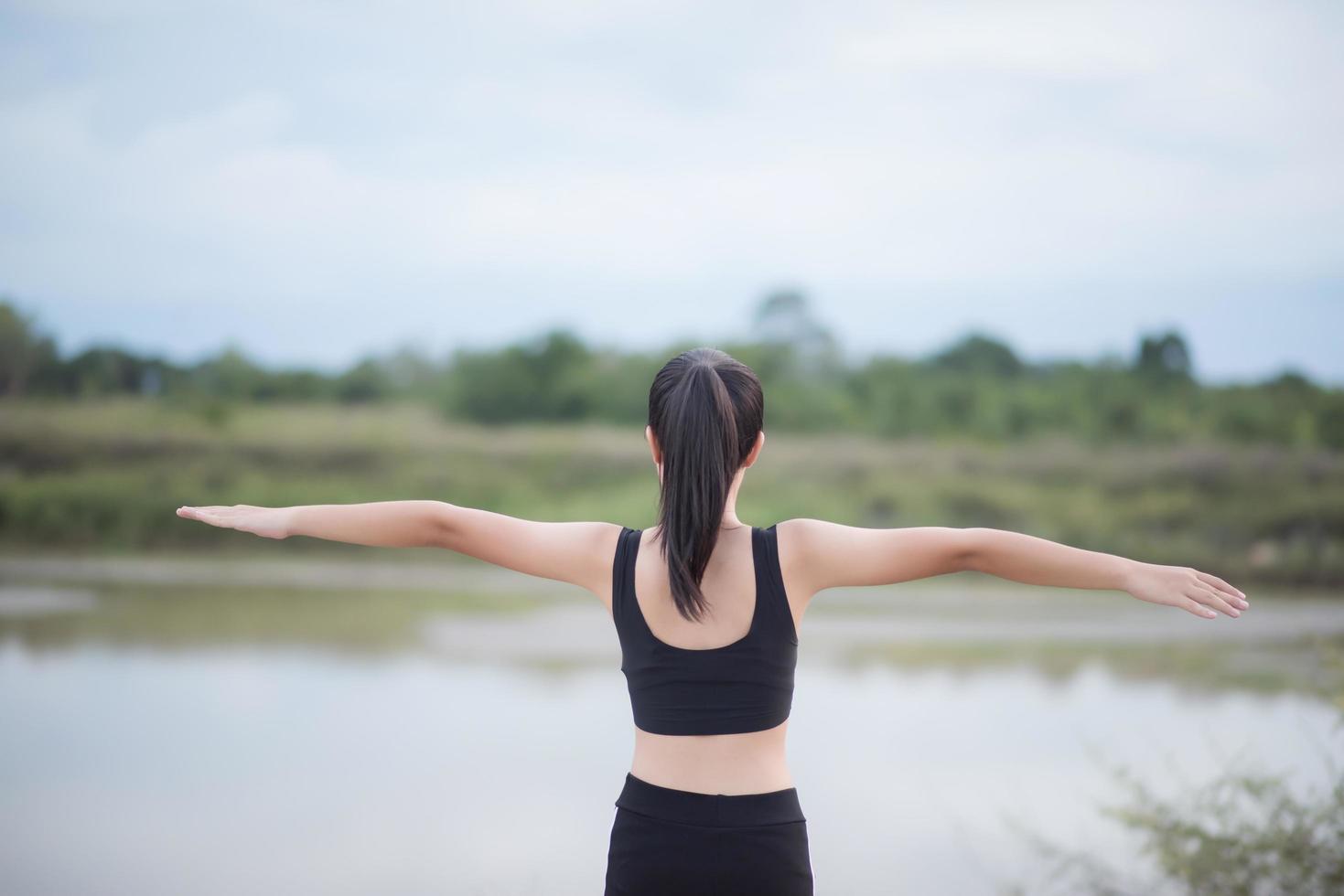 Mujer joven sana calentando al aire libre para entrenar foto