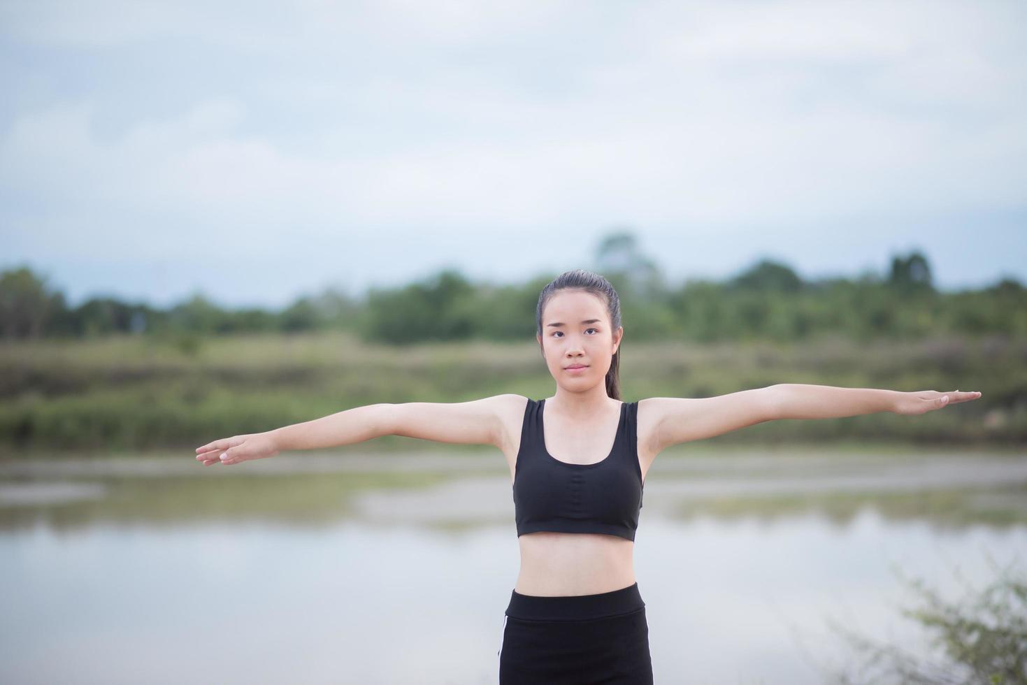 Mujer joven sana calentando al aire libre para entrenar foto