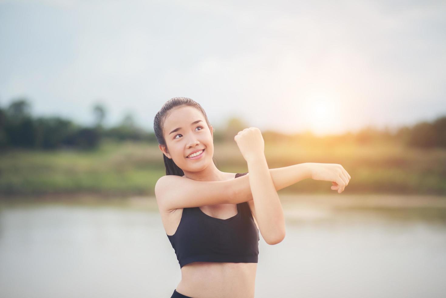 Mujer joven sana calentando al aire libre para entrenar foto