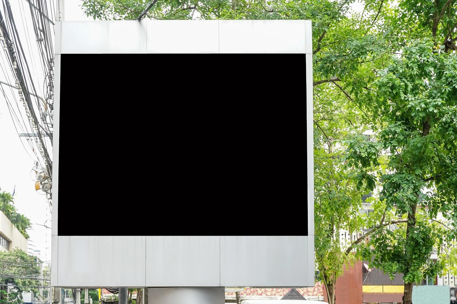 Billboard with empty screen for outdoor advertising, against blue cloudy sky photo