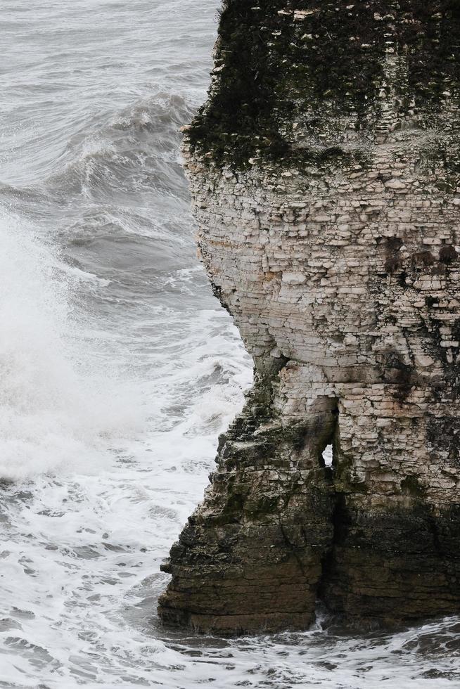 ondas de agua que golpean la montaña rocosa durante el día foto