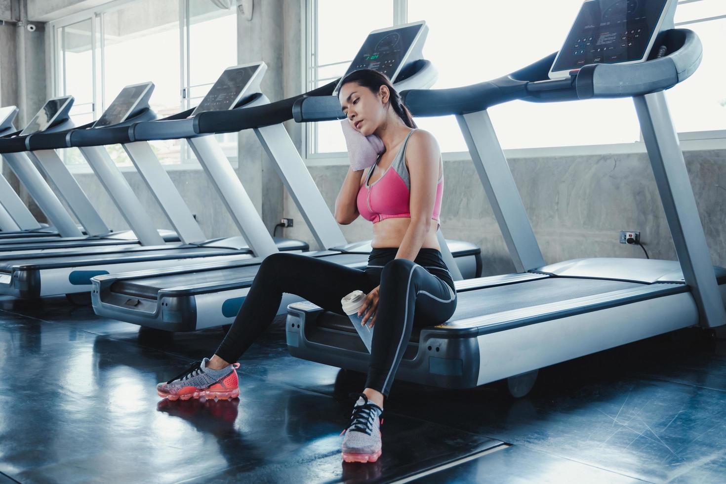 Asian women hold flask, sit and rest tired on the treadmill. photo