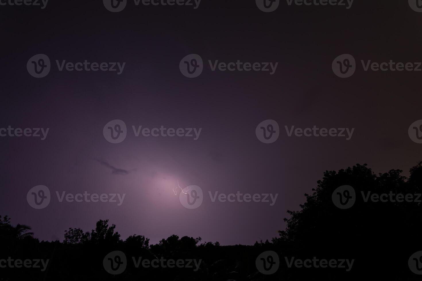 A lightning bolt is seen in the sky over a dark sky photo