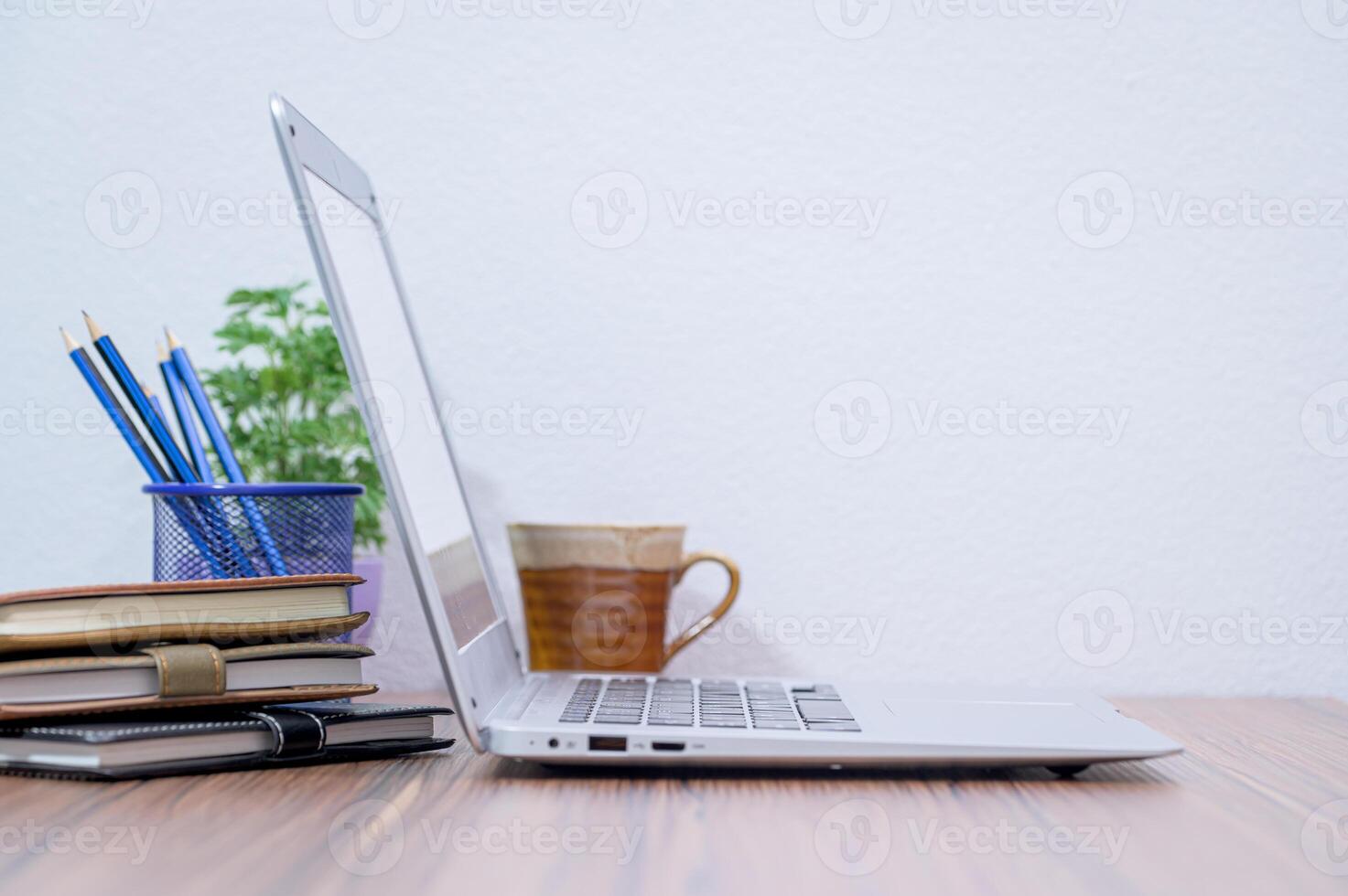 A laptop sitting on a desk with a cup of coffee and a book photo