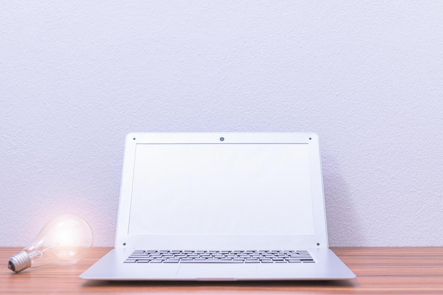 Laptop and light bulb on the desk photo