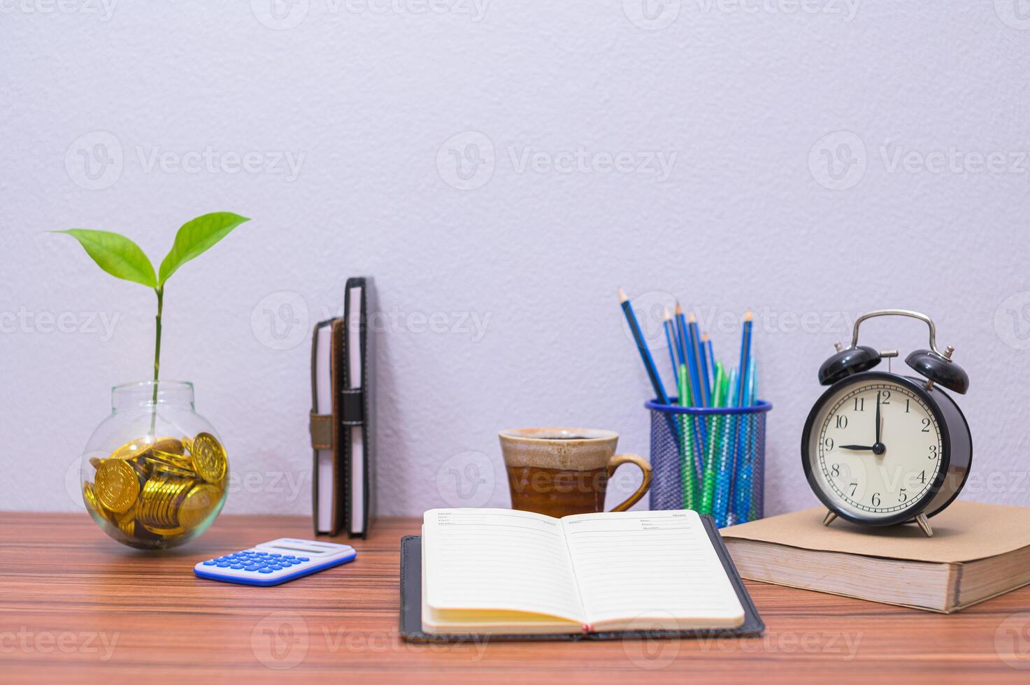 A desk with a plant, books, and a clock photo