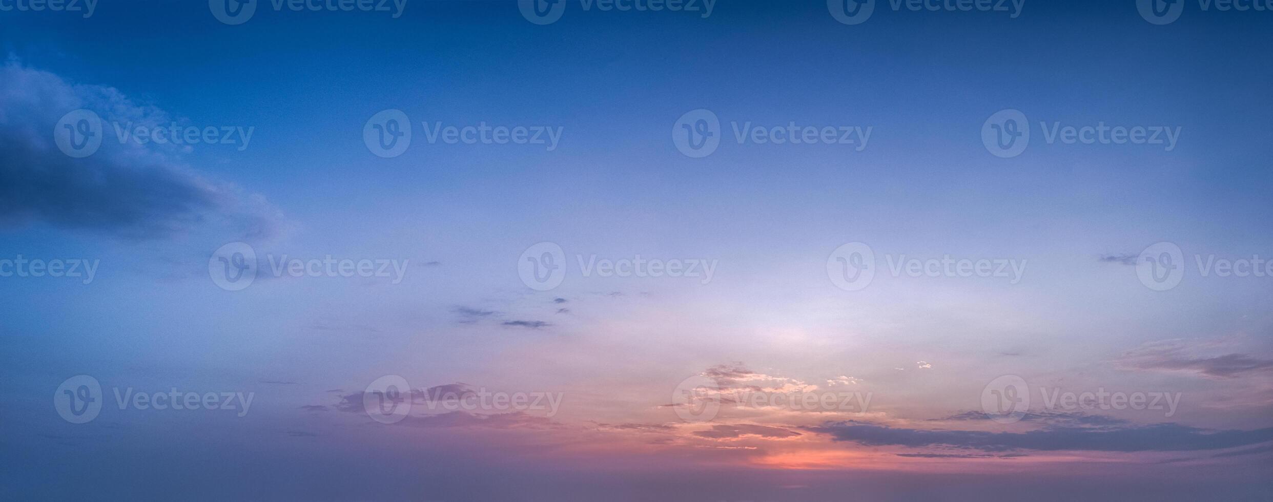 A sunset over the ocean with clouds and a blue sky photo