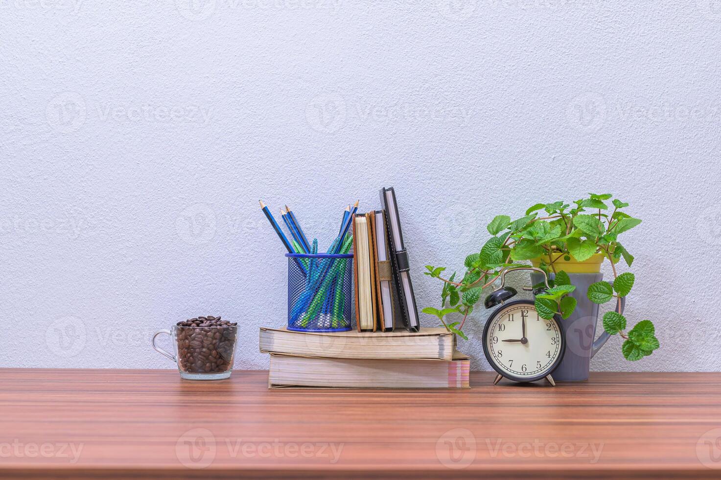 A desk with books, a clock, and a plant photo