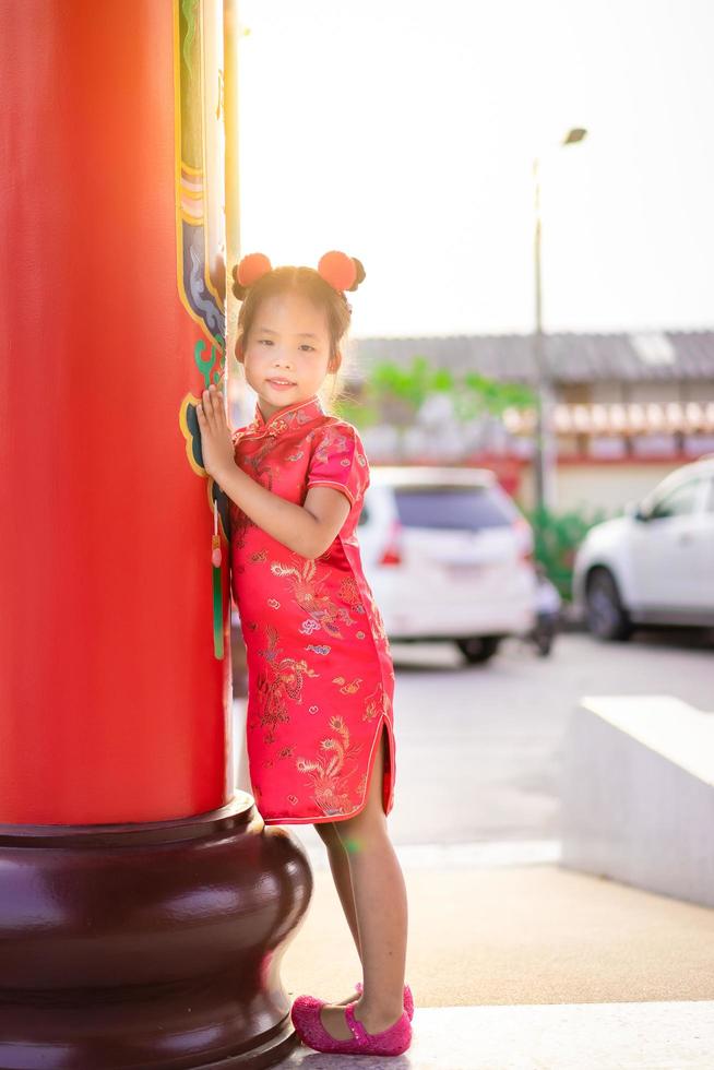 Cute little asian girl in chinese traditional dress smiling in the temple. Happy chinese new year concept photo