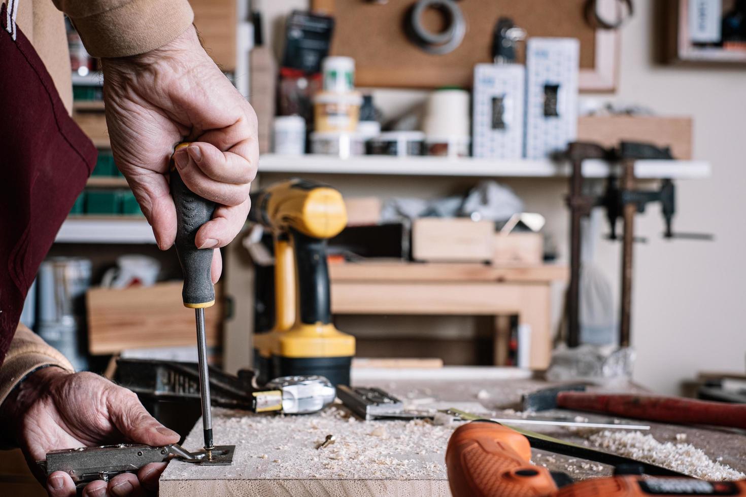 Carpenter screwing a hinge to a board with a screwdriver photo