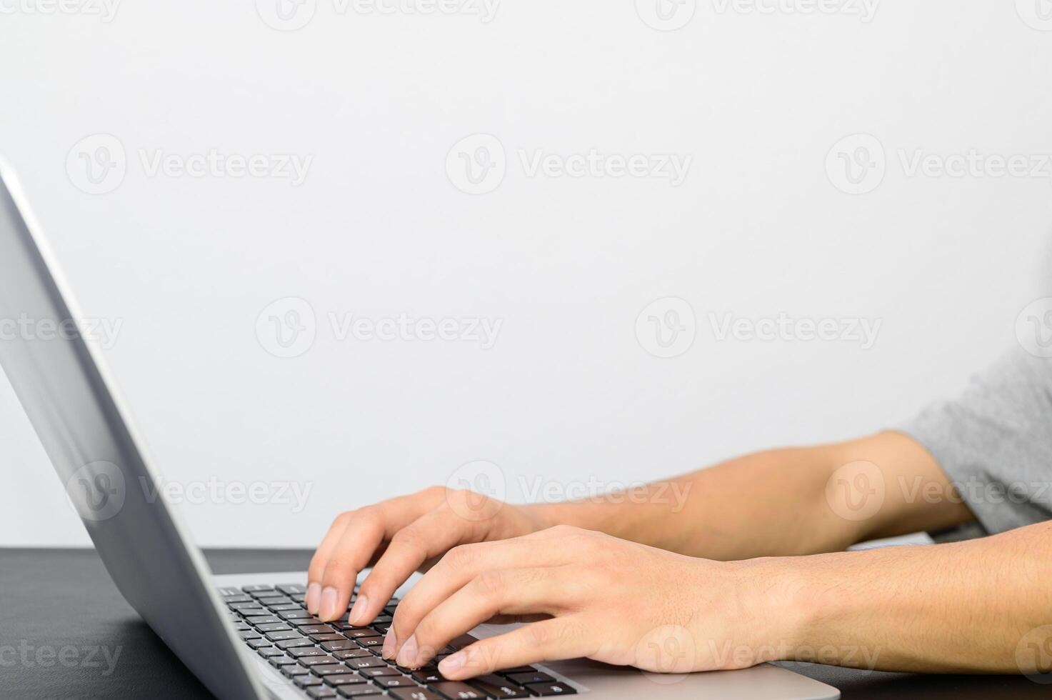 A man is typing on a laptop computer photo