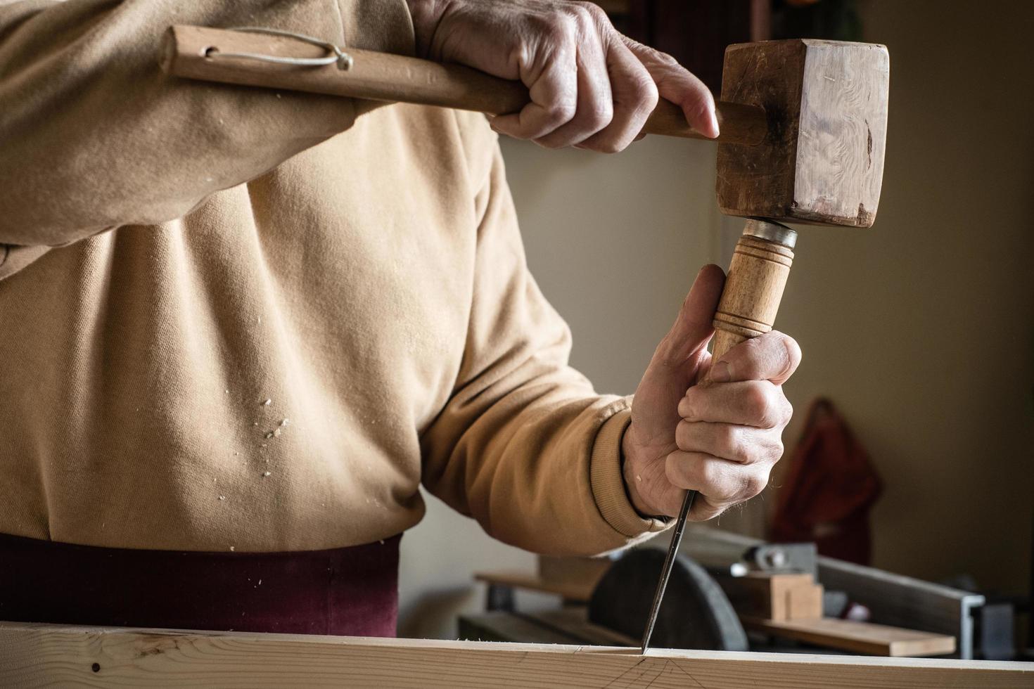 carpintero trabajando con un martillo de madera y una gubia foto