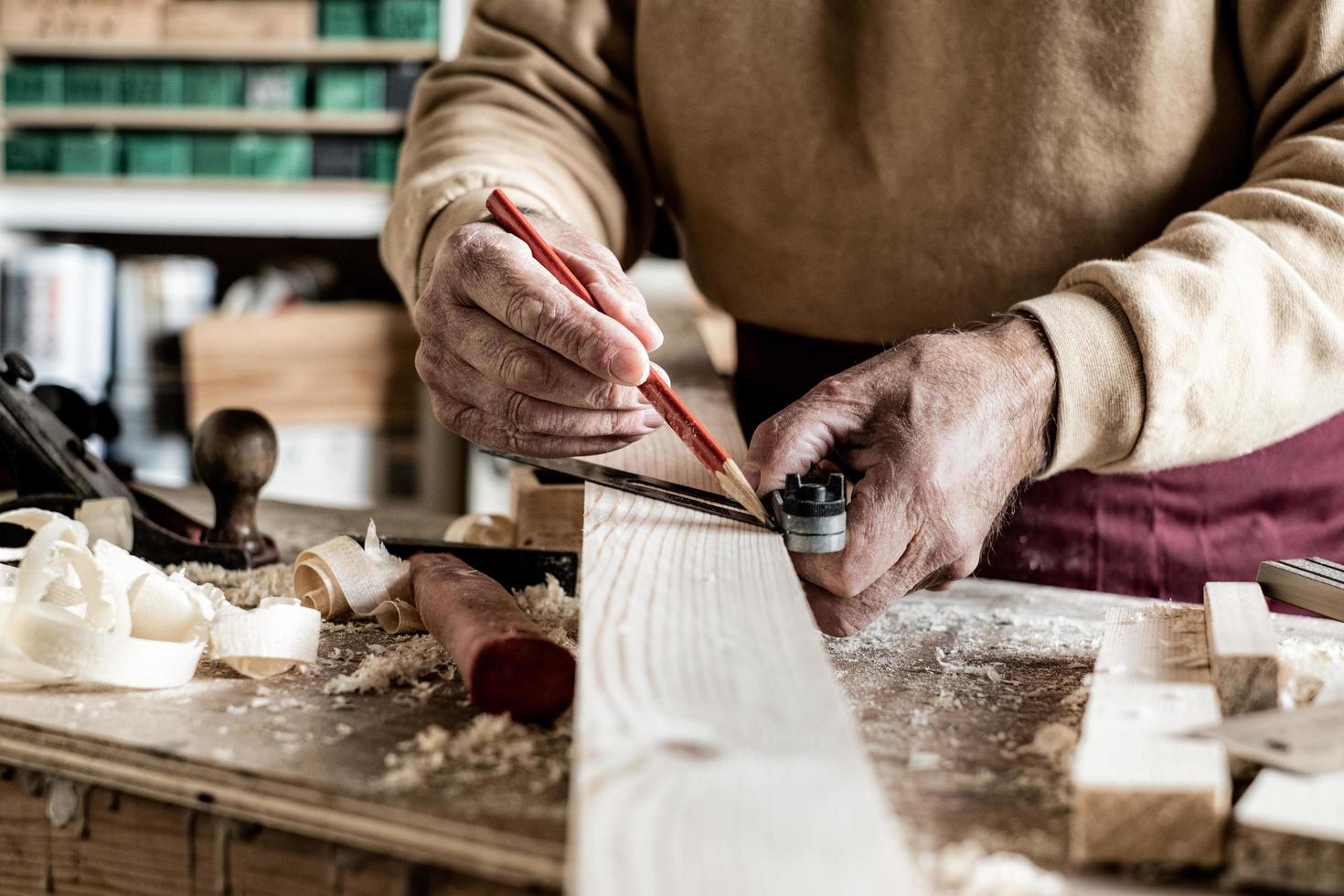 Carpenter making measurements with a pencil and a metal ruler on wooden plank photo