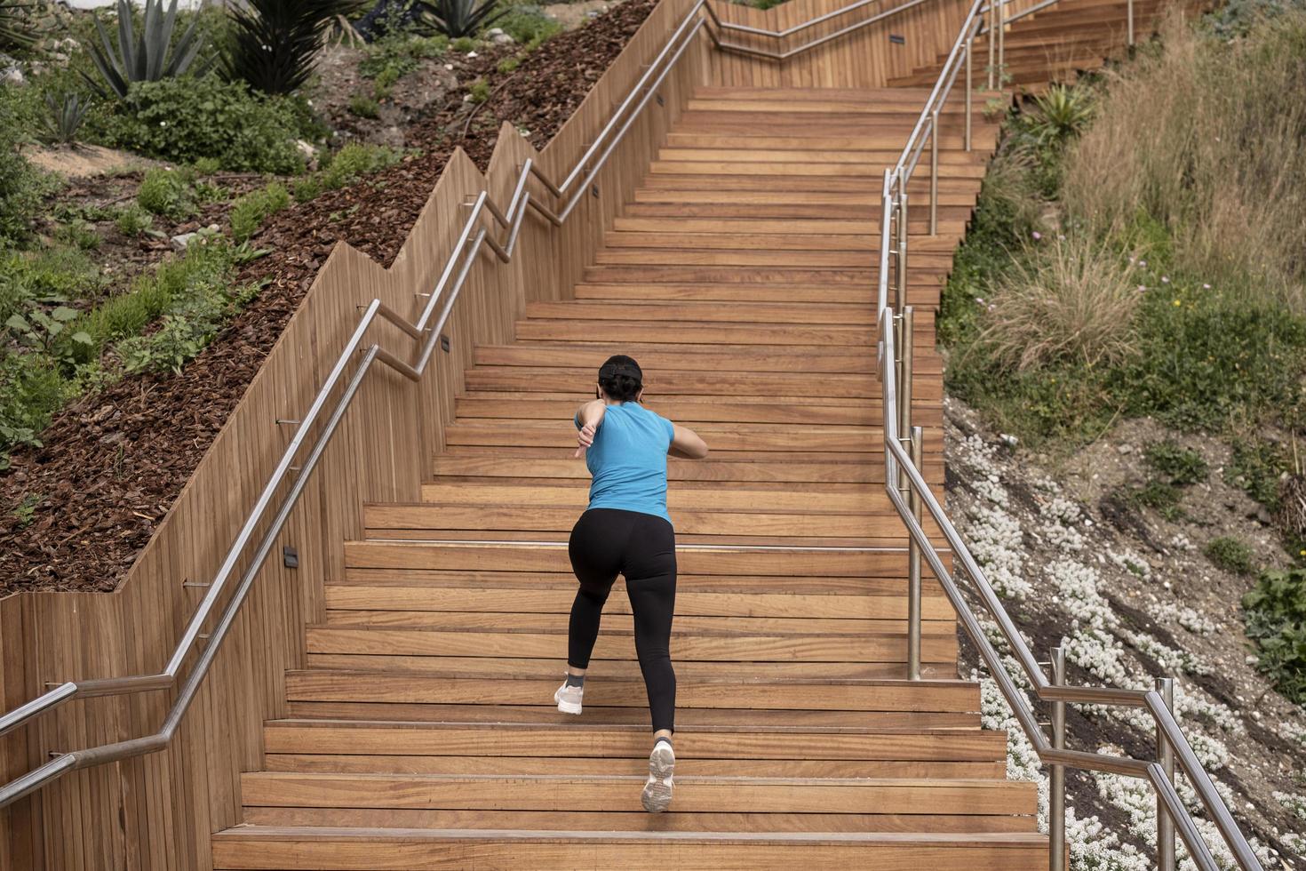 woman running in a blue shirt and climbing a wooden staircase photo