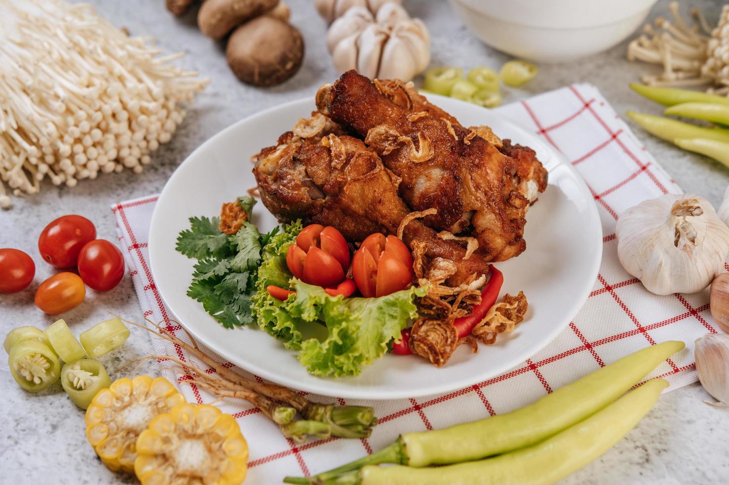 Fried chicken legs with tomato, chili, fried onion, lettuce, corn and mushroom photo