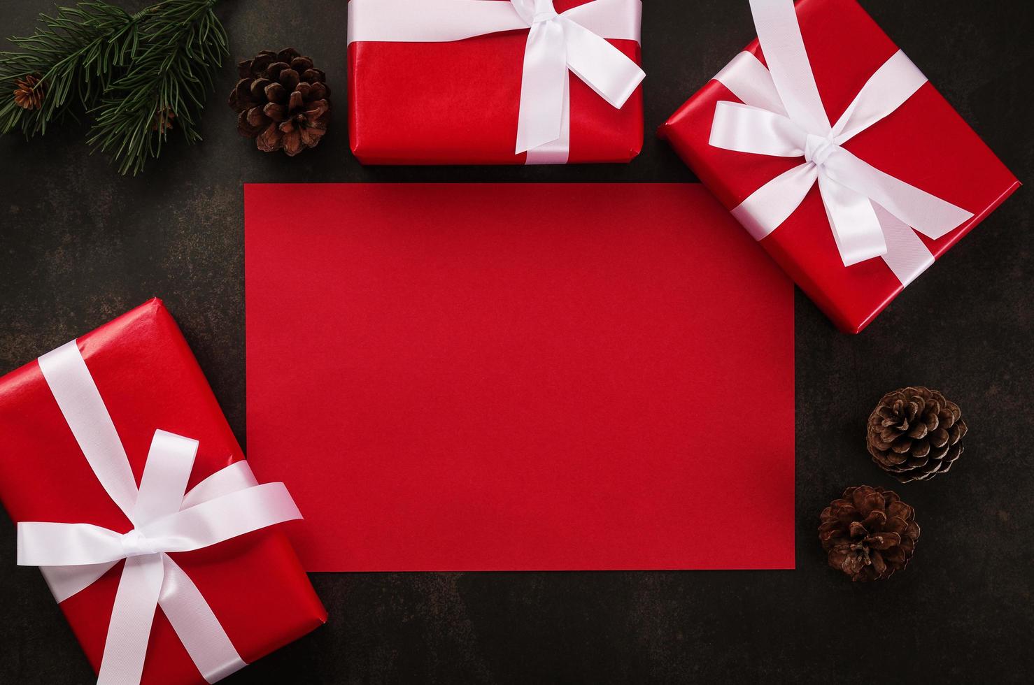 Maqueta de tarjeta de felicitación roja en blanco con adornos de regalo de Navidad sobre fondo grunge foto