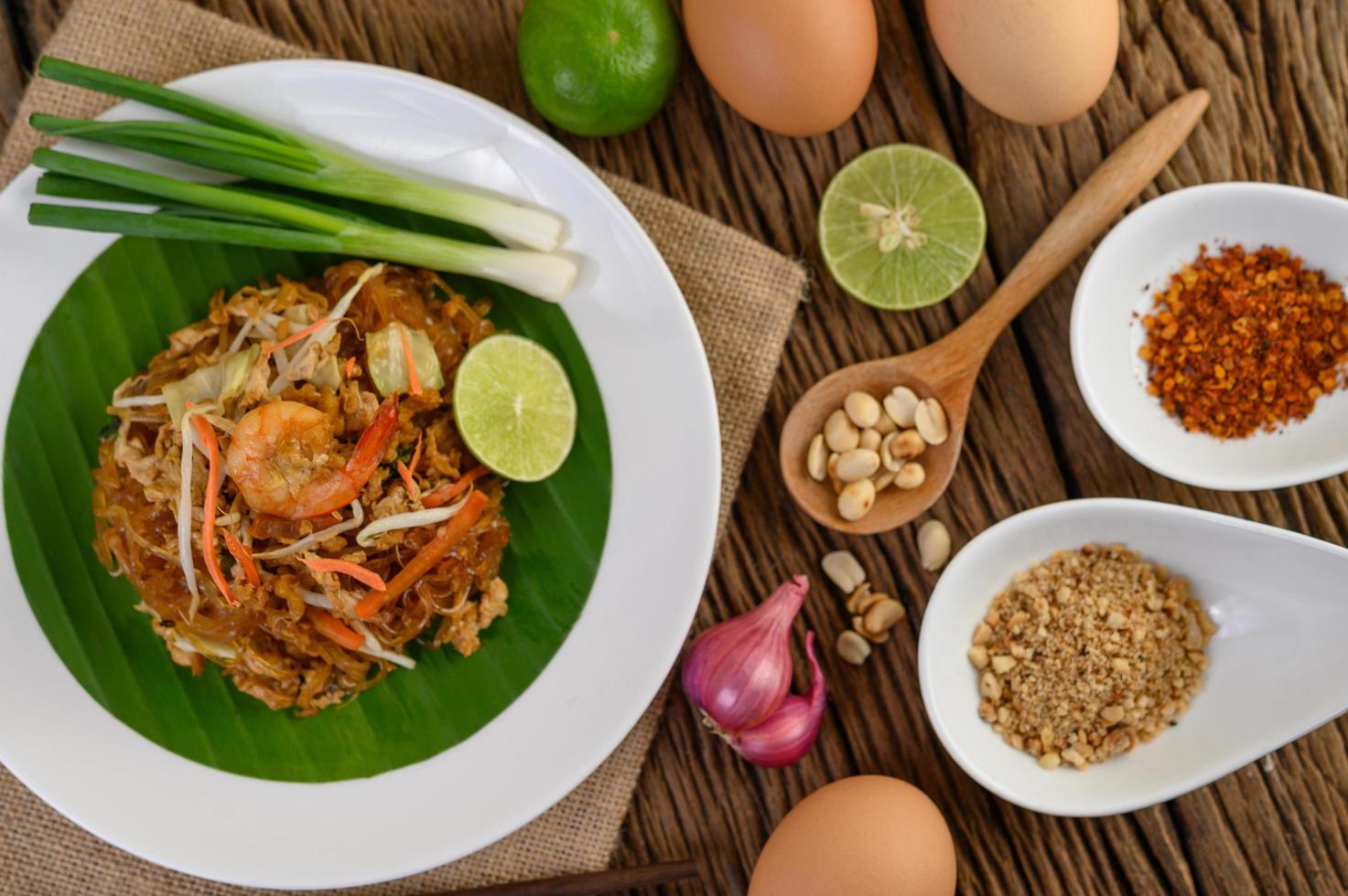 pad thai camarones en un bol con huevos, cebolleta y condimentos foto