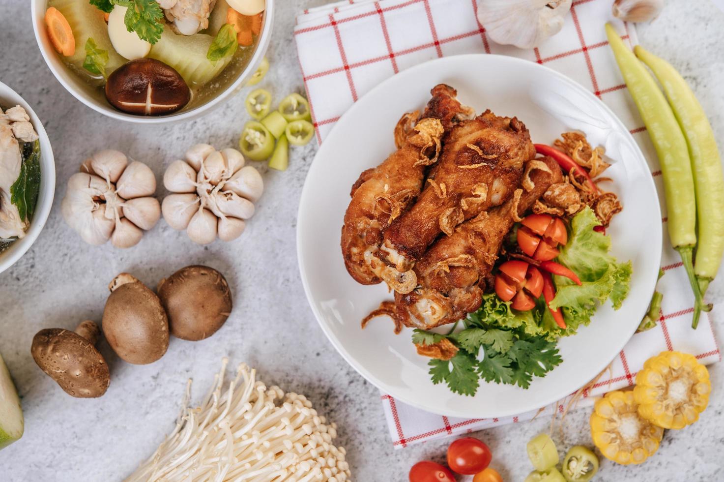 Fried chicken legs with tomato, chili, fried onion, lettuce, corn and mushroom photo