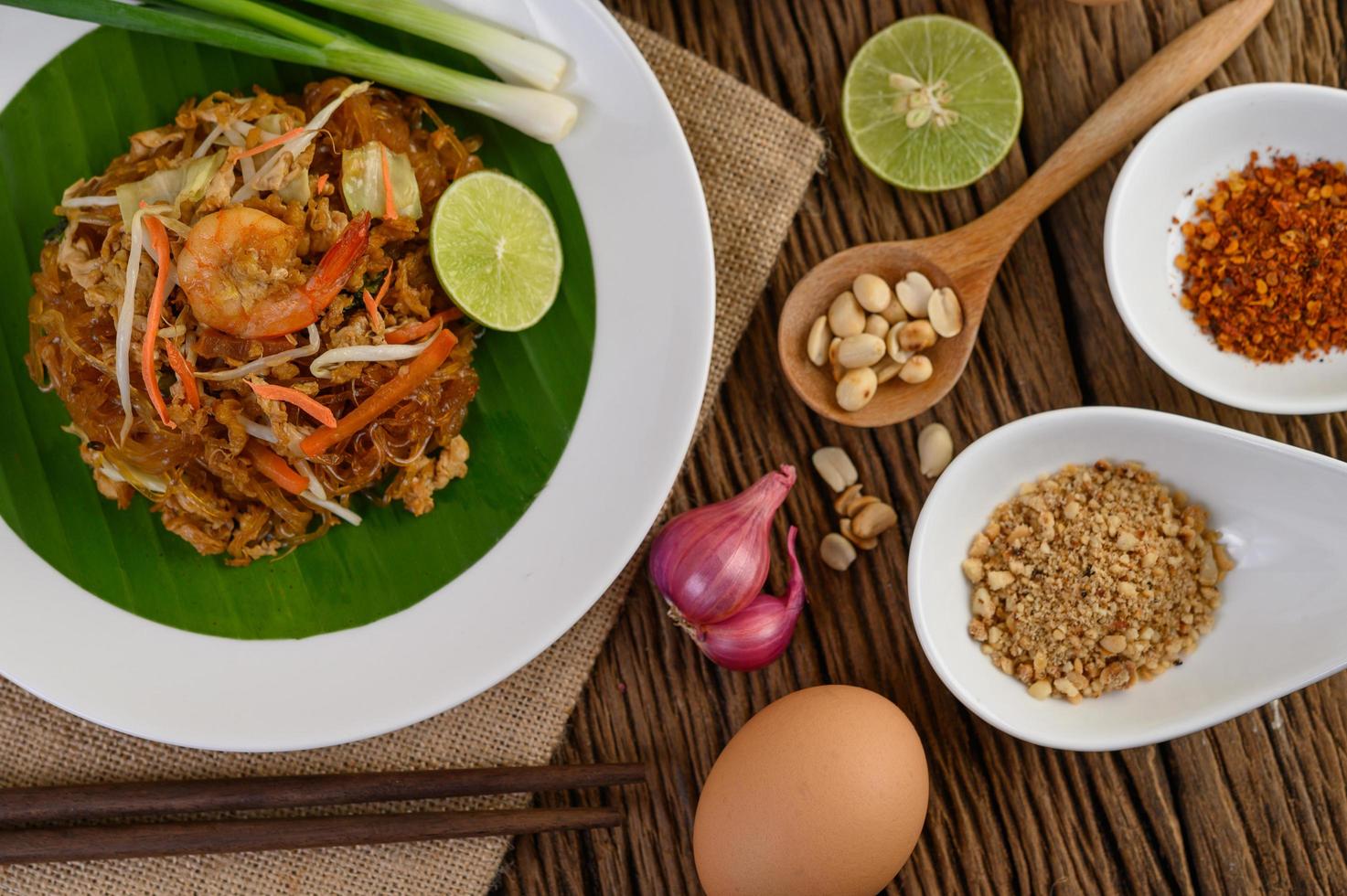 pad thai camarones en un bol con huevos, cebolleta y condimentos foto