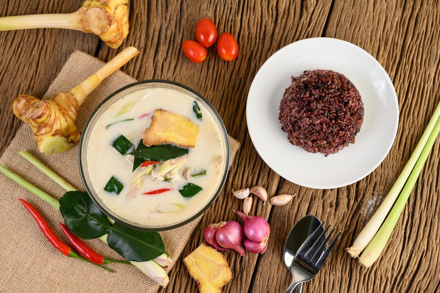 tom kha kai, sopa de coco tailandesa sobre tabla de cocina de madera foto