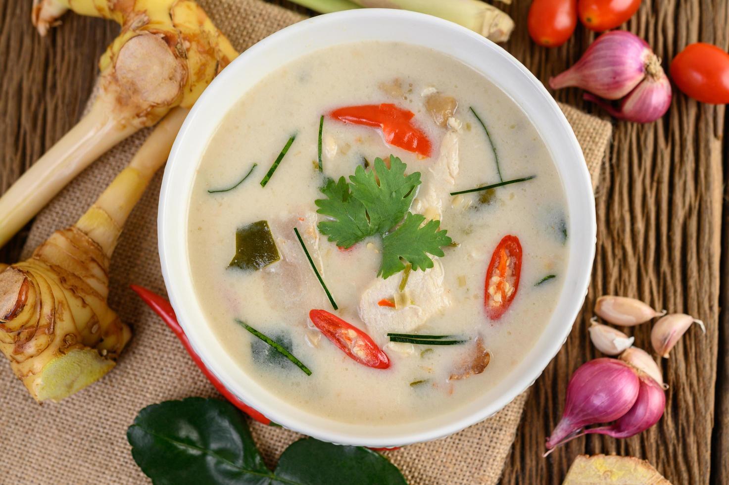 tom kha kai, sopa de coco tailandesa sobre tabla de cocina de madera foto