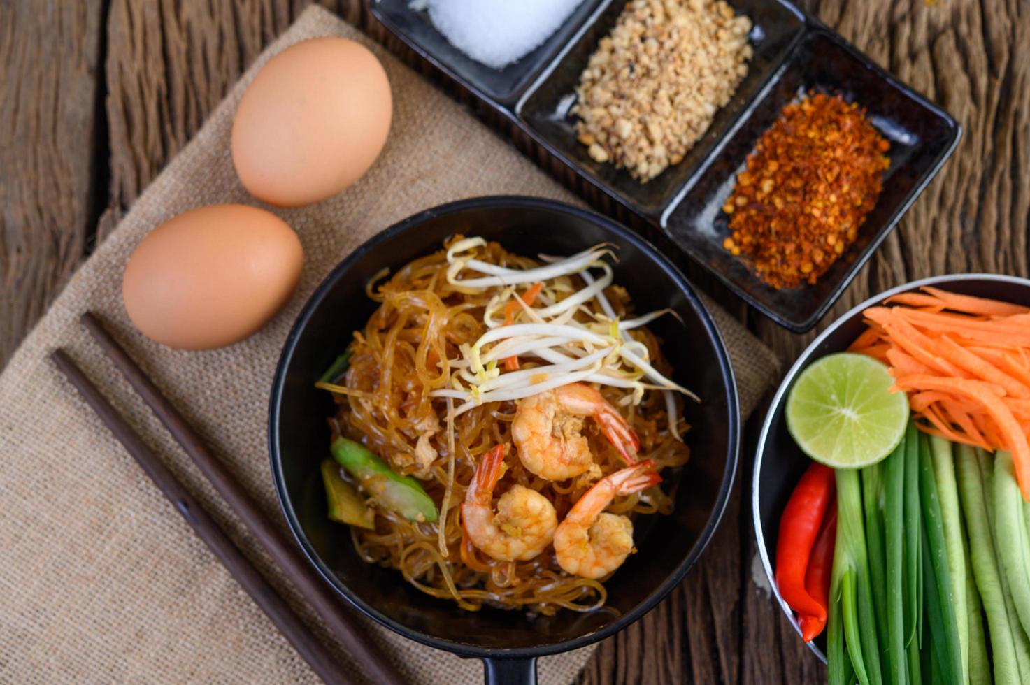 Pad thai shrimp in a black pan with eggs and seasoning photo