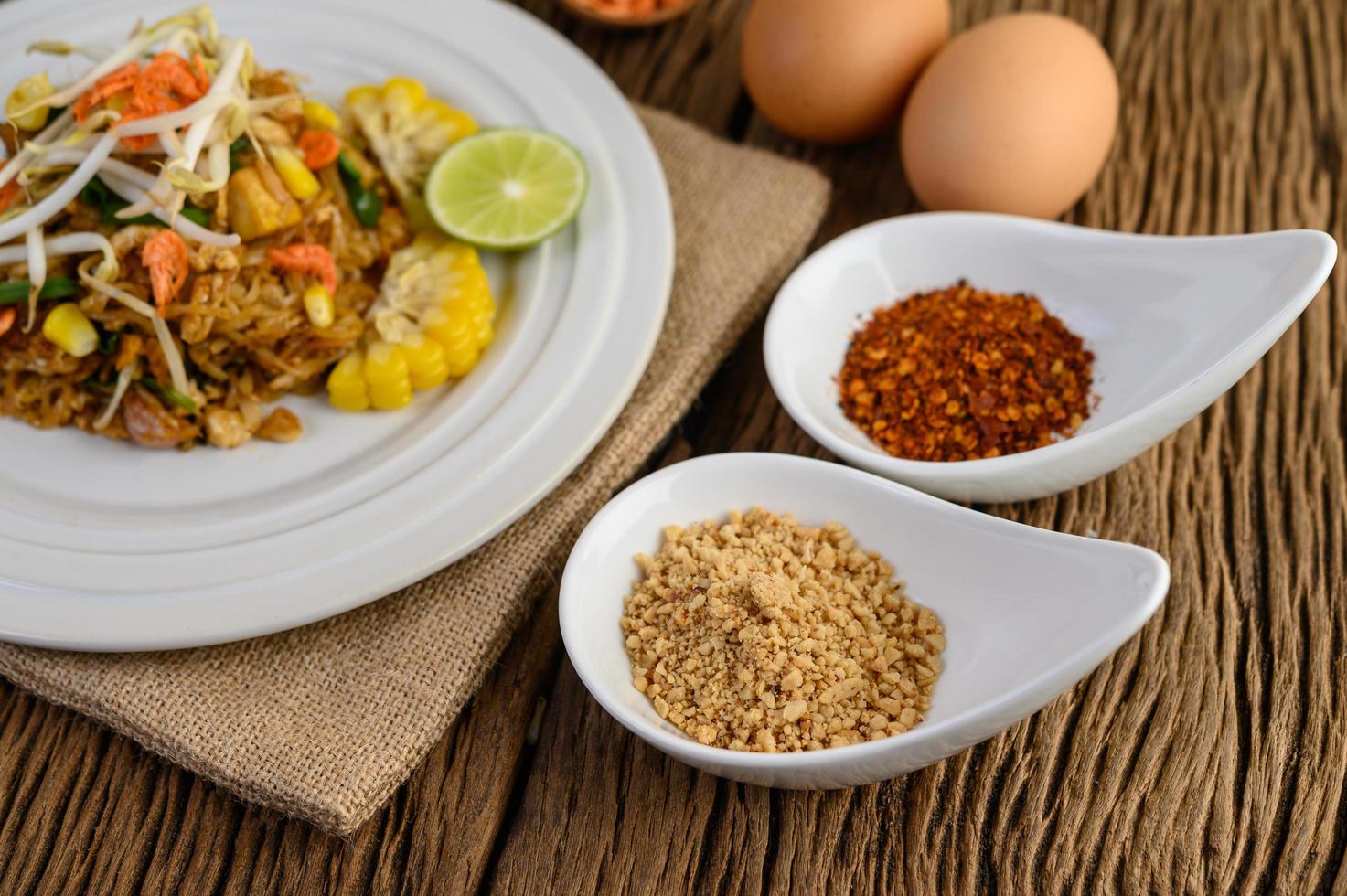 Pad Thai with lemon, eggs and seasoning on a wooden table photo