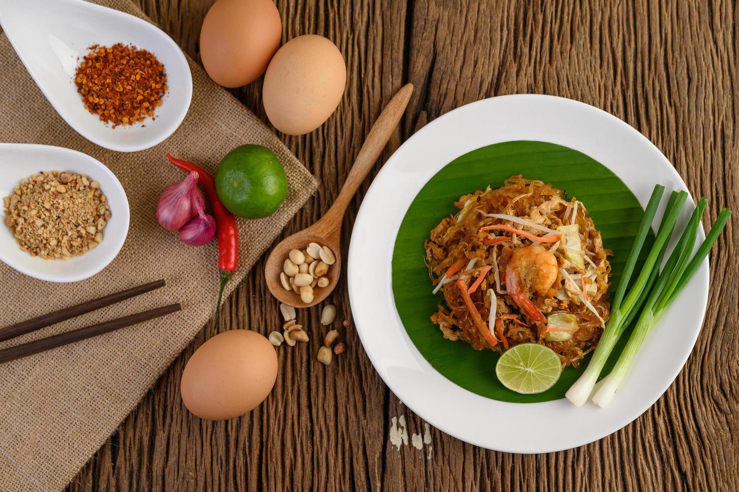 pad thai camarones en un bol con huevos, cebolleta y condimentos foto