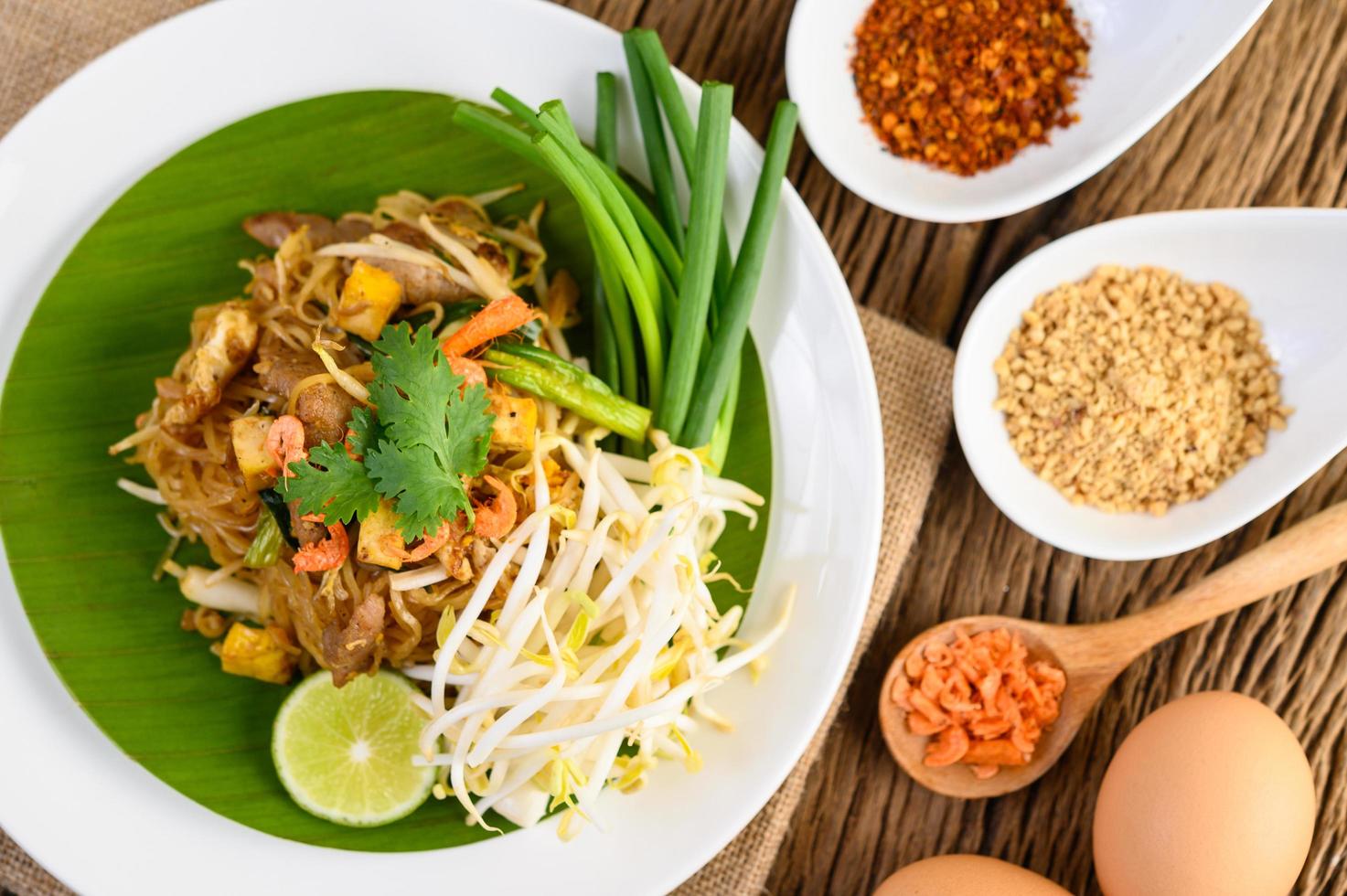 Pad Thai with lemon, eggs and seasoning on a wooden table photo