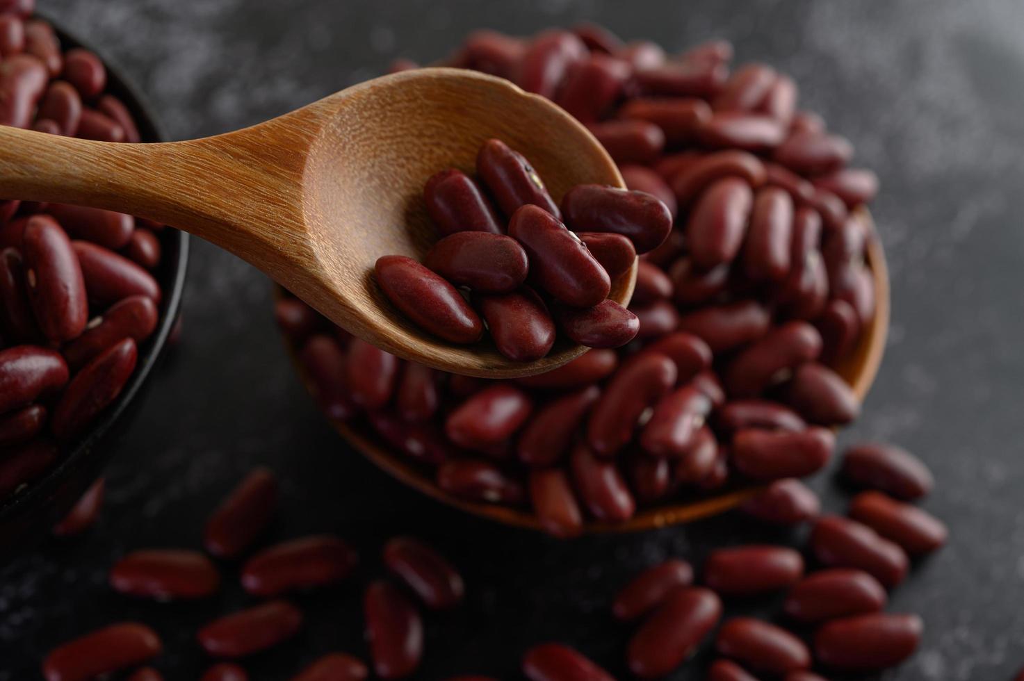 Red beans in wooden bowls on black kitchen surface photo