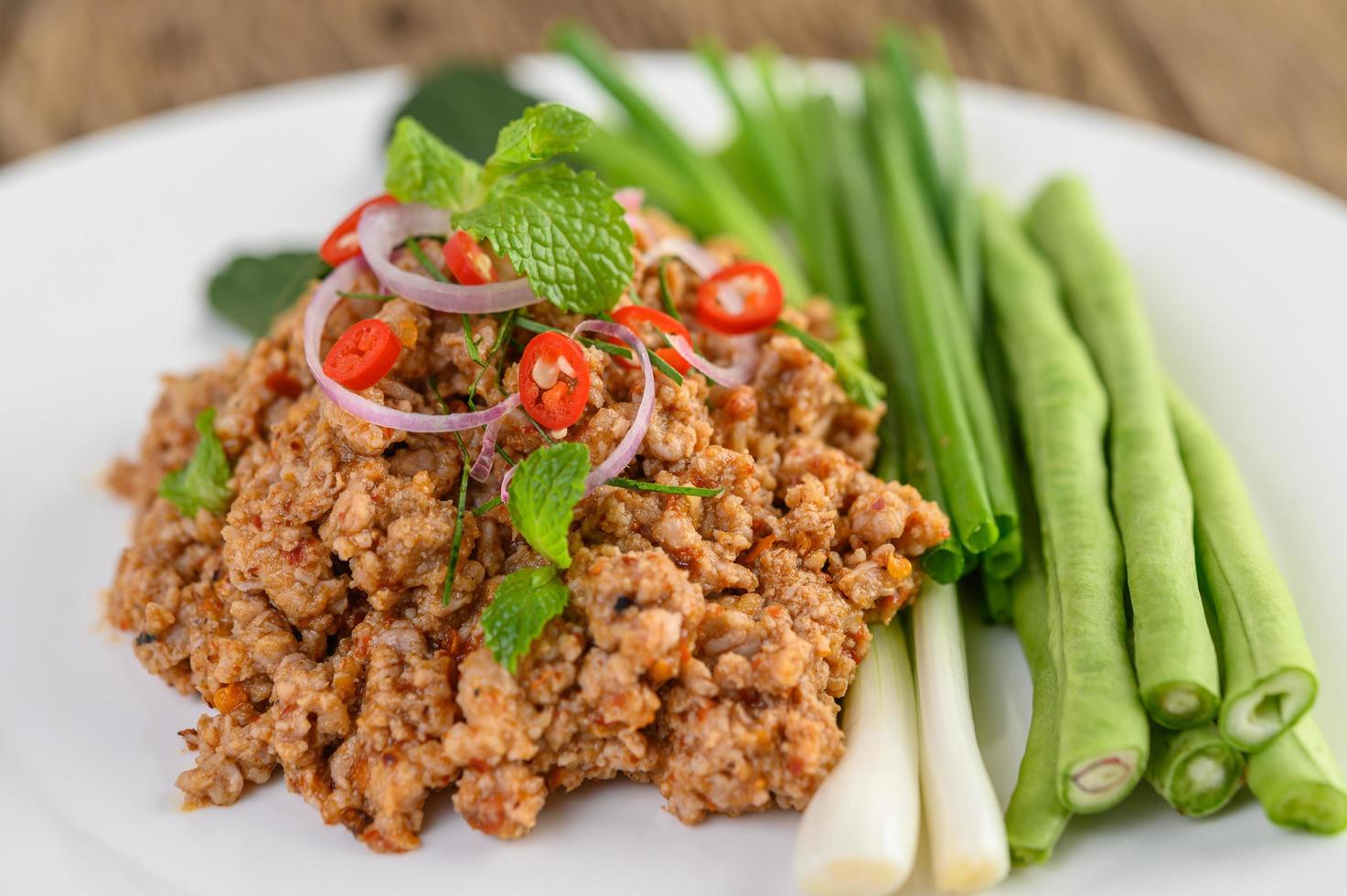 Spicy minced pork salad on green vegetables photo